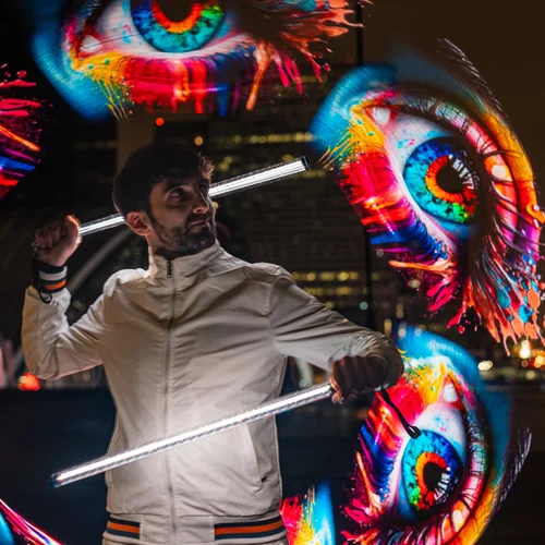 jongleur lumineux qui tient des batons leds avec des yeux en light painting autour de lui